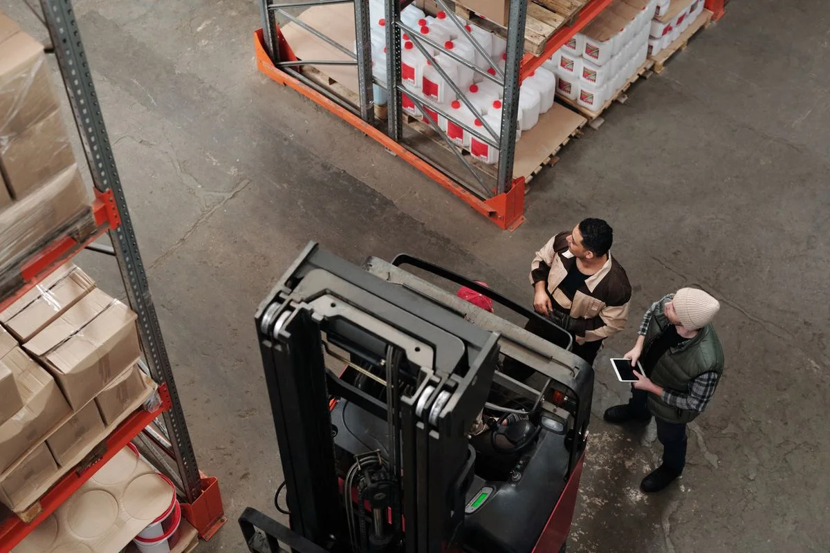 Warehouse employees discussing freight beside a forklift